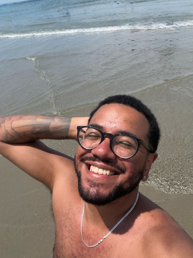 Beach selfie, smiling in the sand with the water behind me